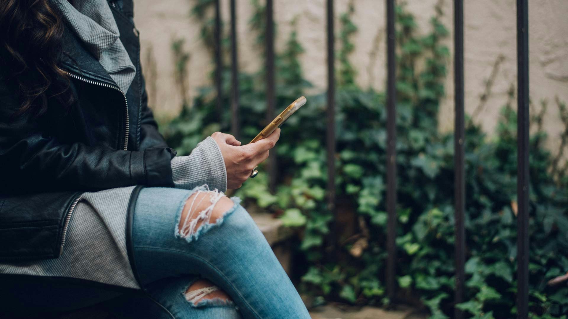 Women Sitting on Bench with Smart Phone in Hand